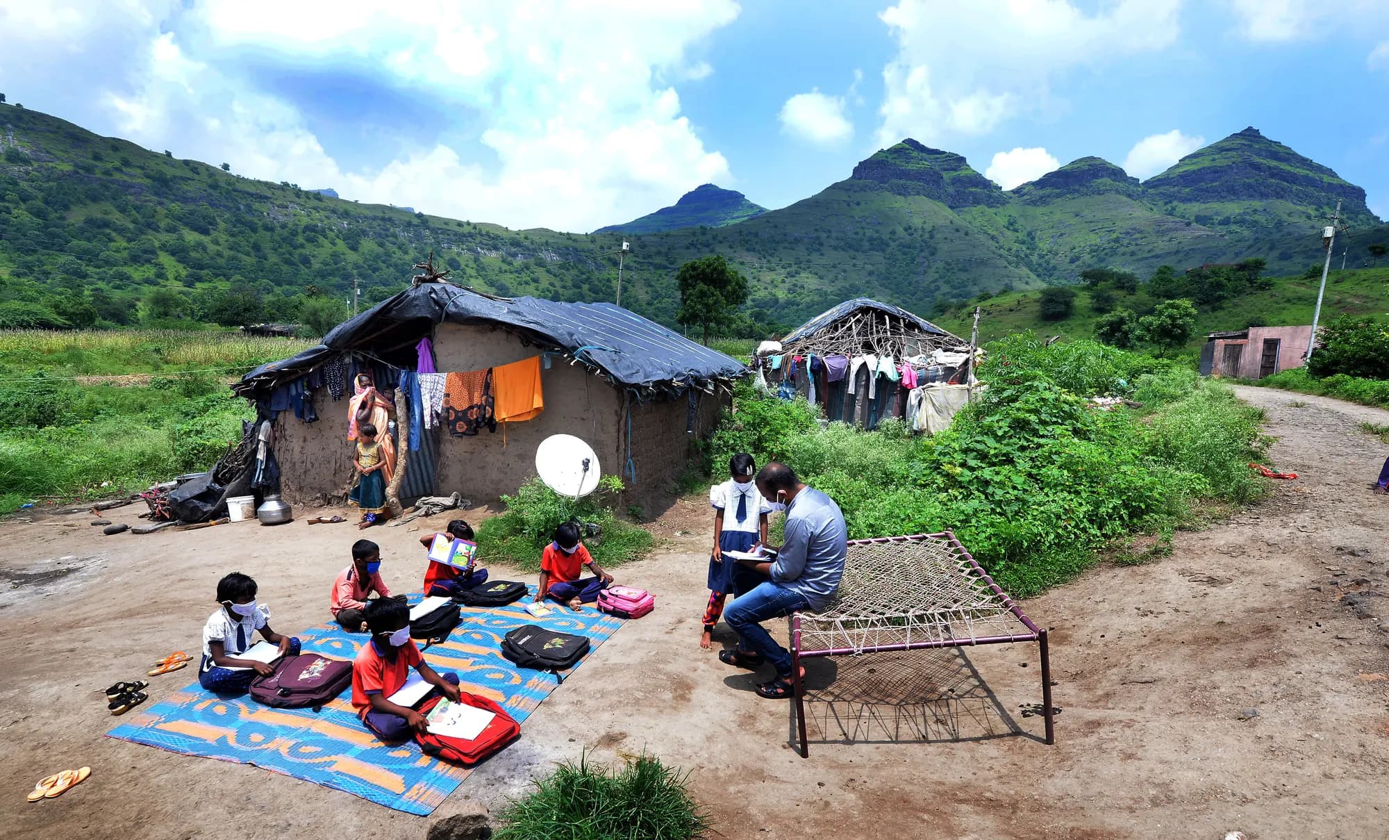 A teacher running an open-air learning session for children in a rural village